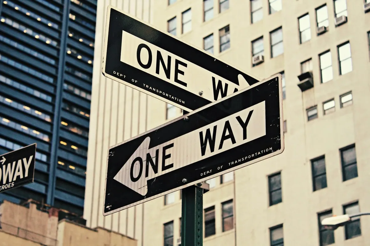 A one-way street sign on an urban road representing systemic barriers